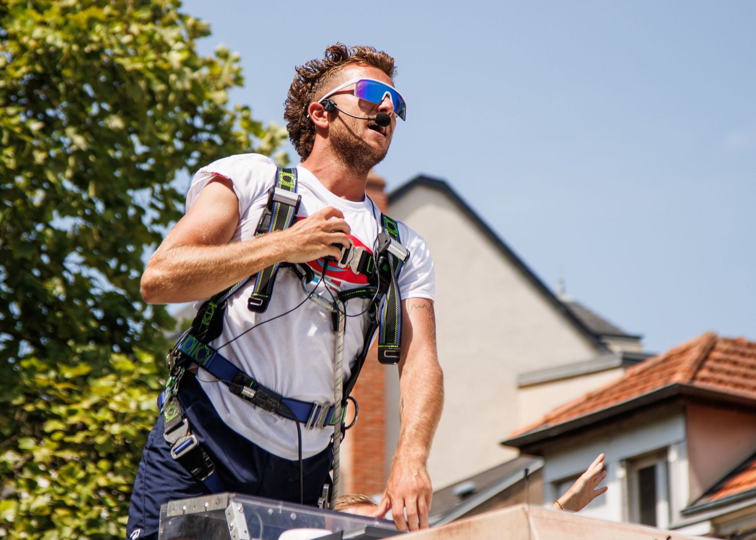 A participant in sunglasses and backpack enjoying the outdoor parade festivities.