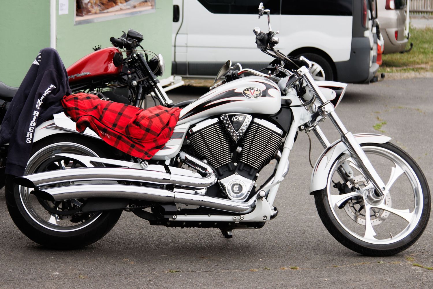 Custom chrome and red motorcycles parked side by side on street.