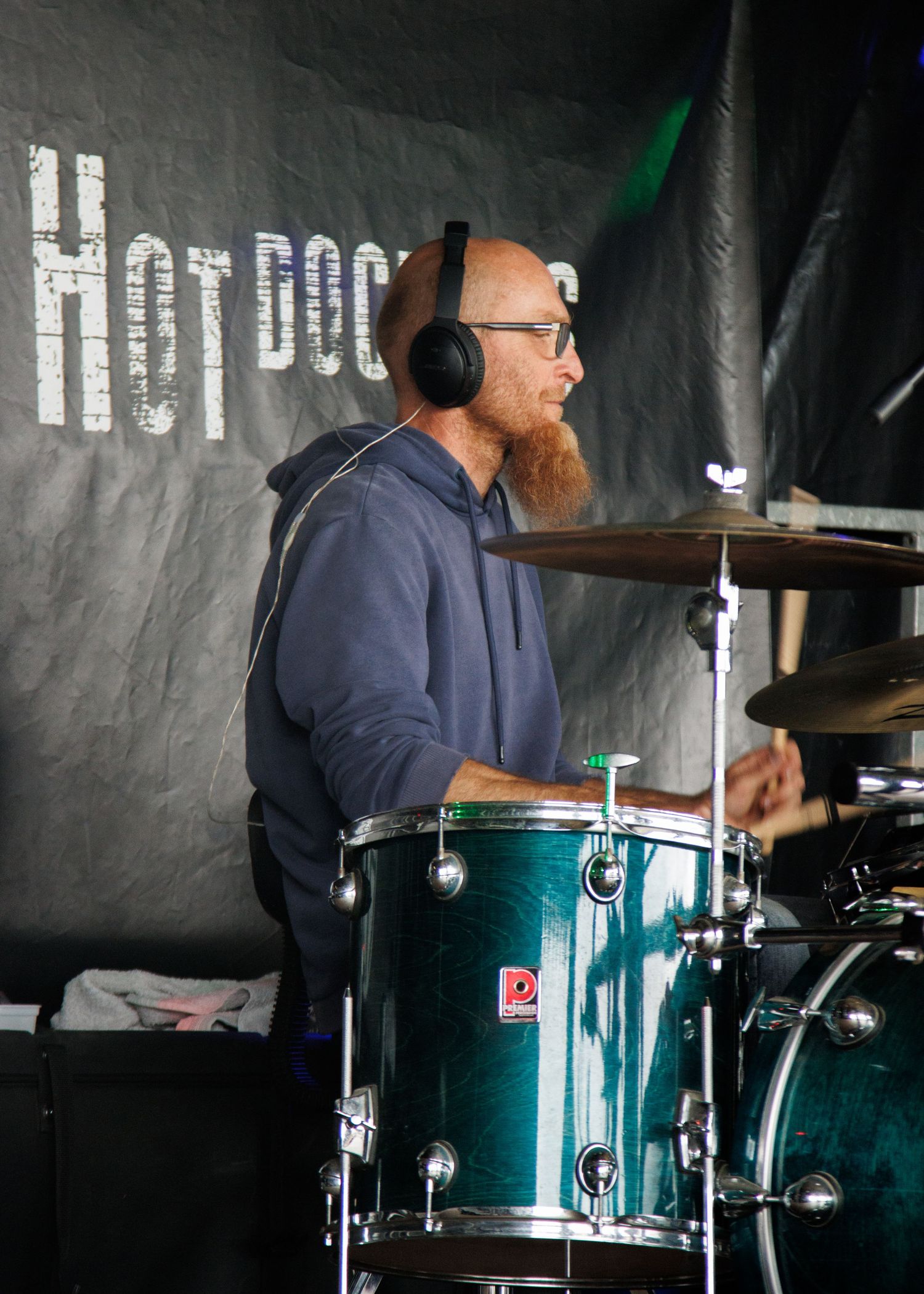 Drummer performing behind a teal drum kit on stage.