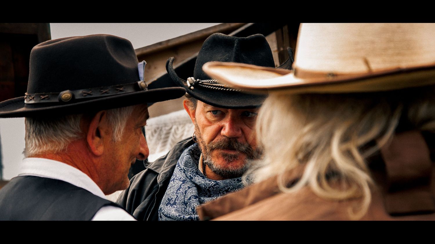 Two people in western attire having an intense conversation during period scene.