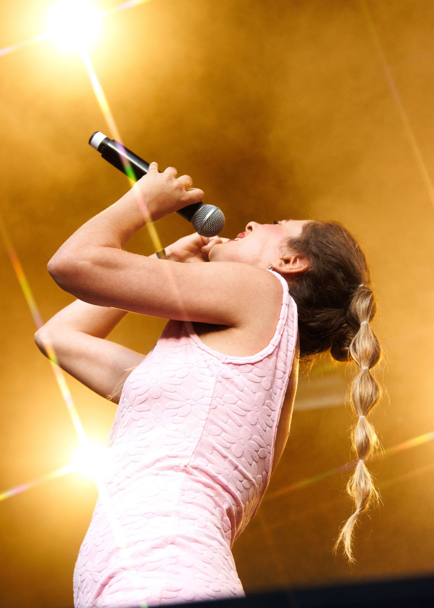 A person in a pink tank top drinks from a bottle against a warm golden background in a sequence of photos.