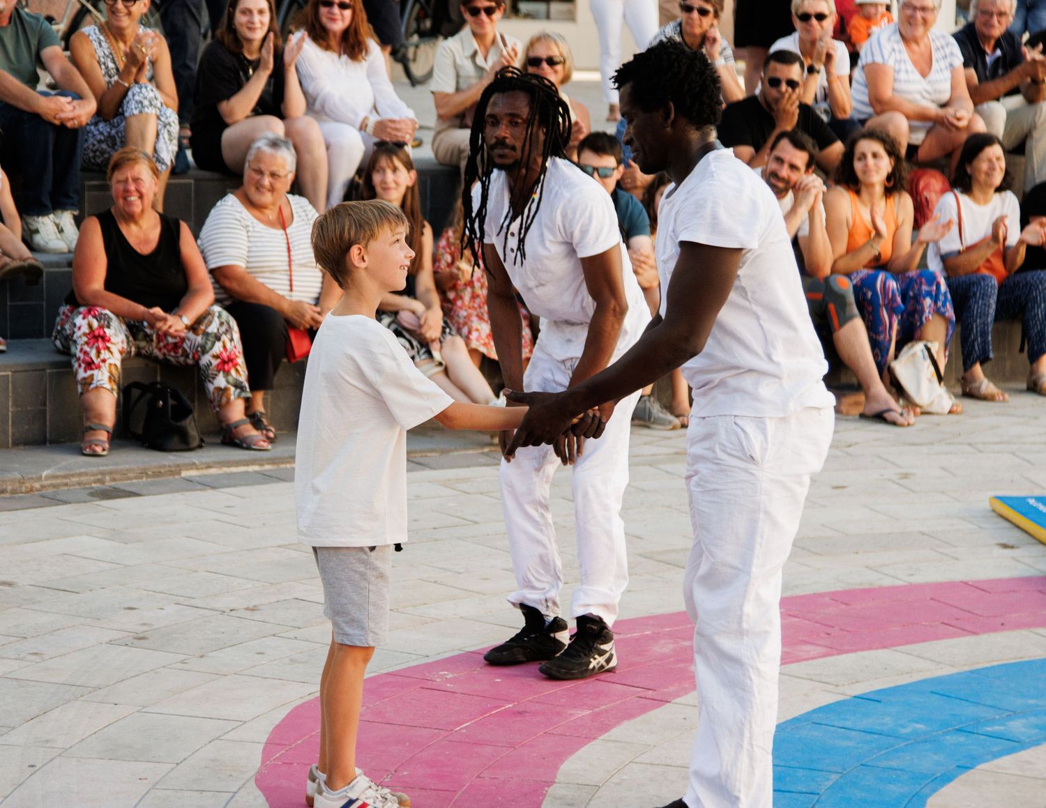 Street performers interact with a young audience member during an outdoor show.