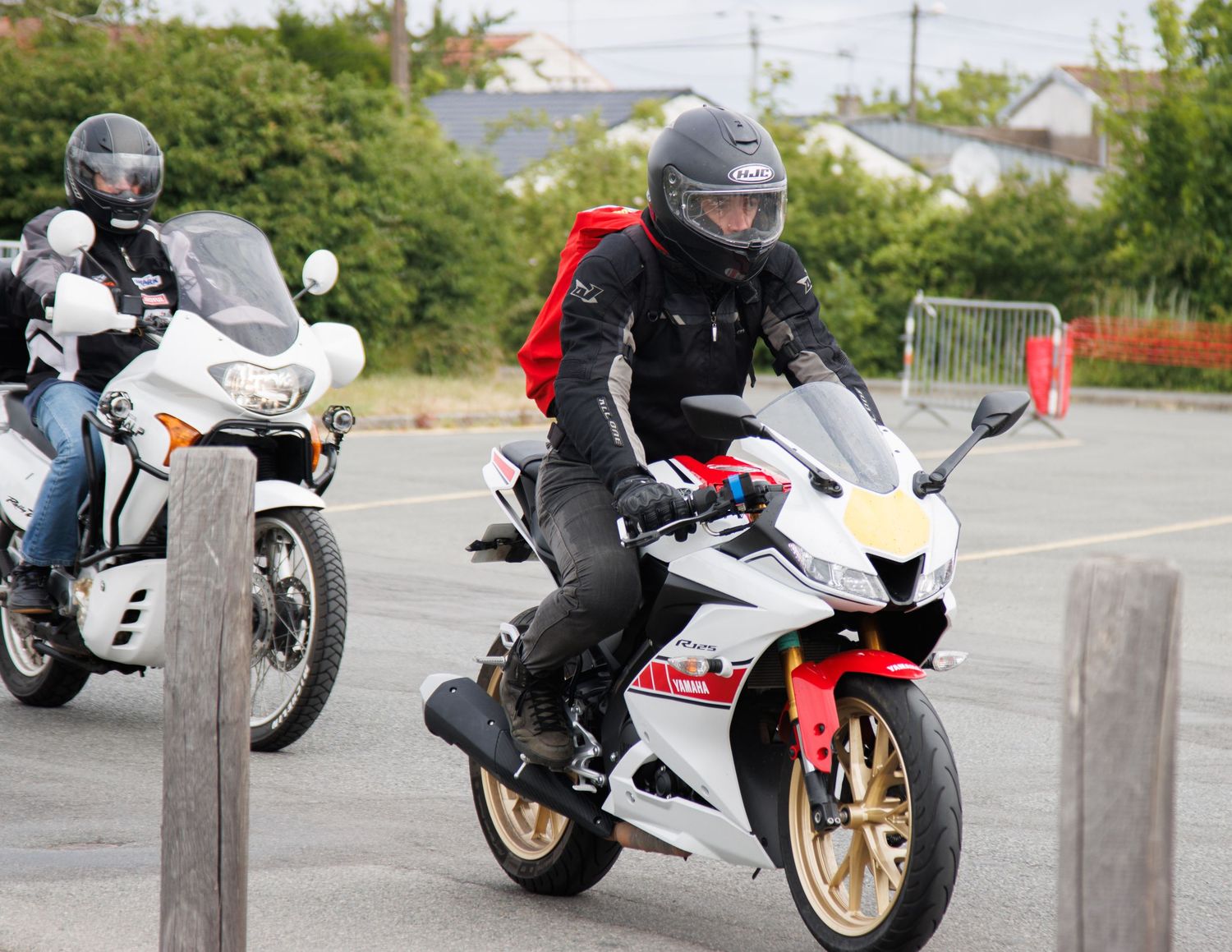 Sport bikes racing down road with protective barriers visible in foreground.