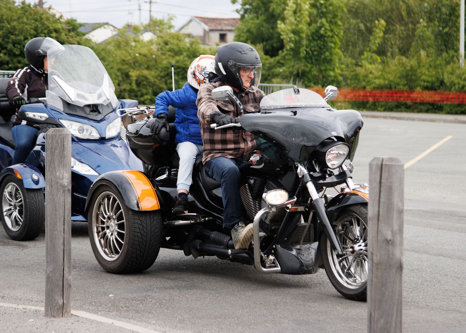 Two motorcycles parked side by side in a lot, including a Can-Am Spyder and custom bike.