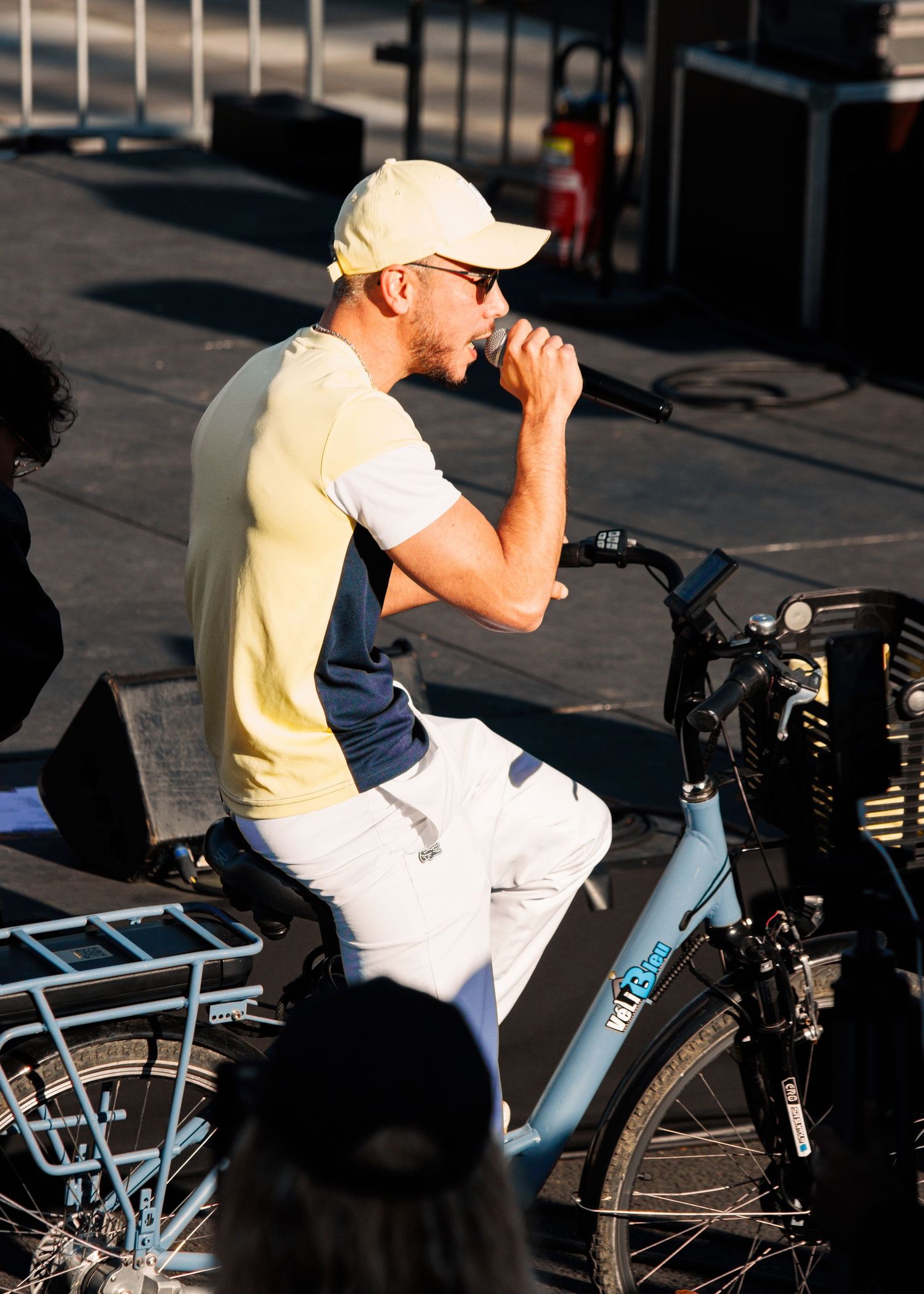 Artist performs next to bicycle during outdoor daytime concert.