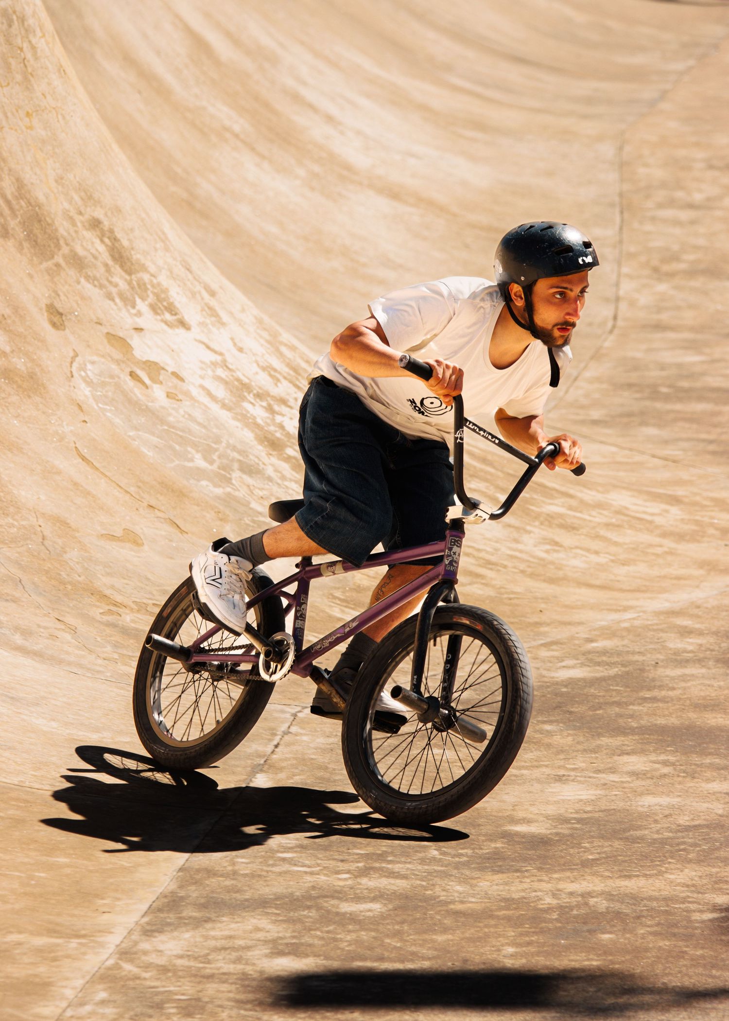 BMX rider navigating steep curved ramp at skate park during performance.