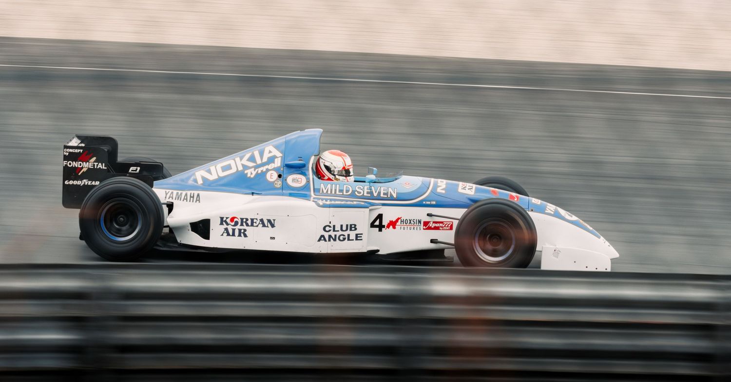 White formula racing car with number 4 accelerates through racetrack section.
