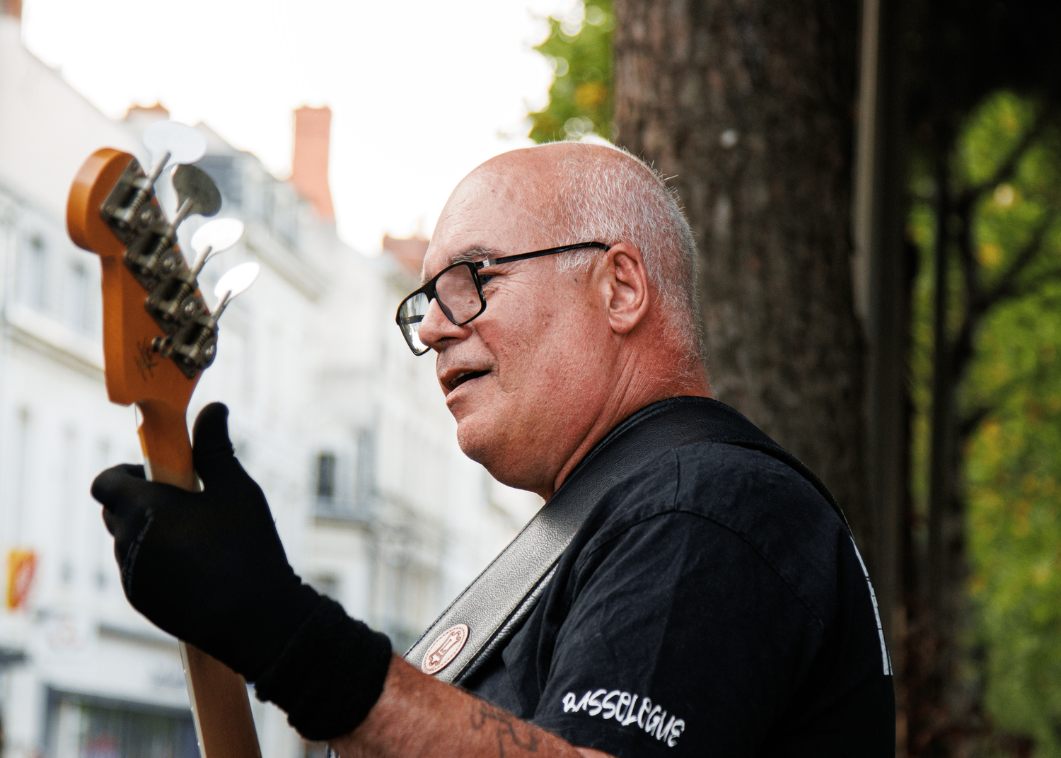 Musician in black t-shirt playing guitar at outdoor performance venue.