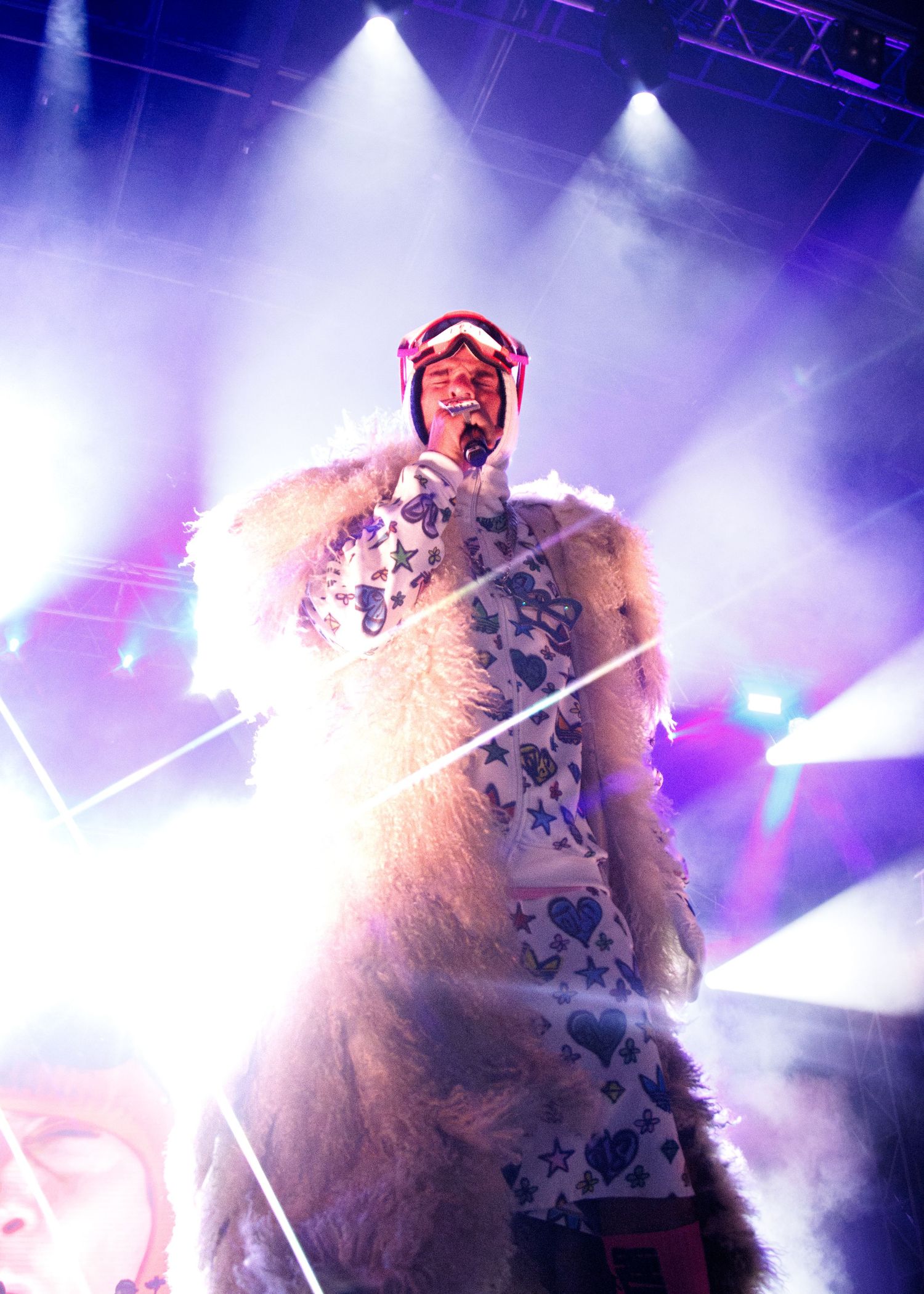 Concert performer illuminated by purple stage lights creates dynamic silhouette against atmospheric haze during live show.