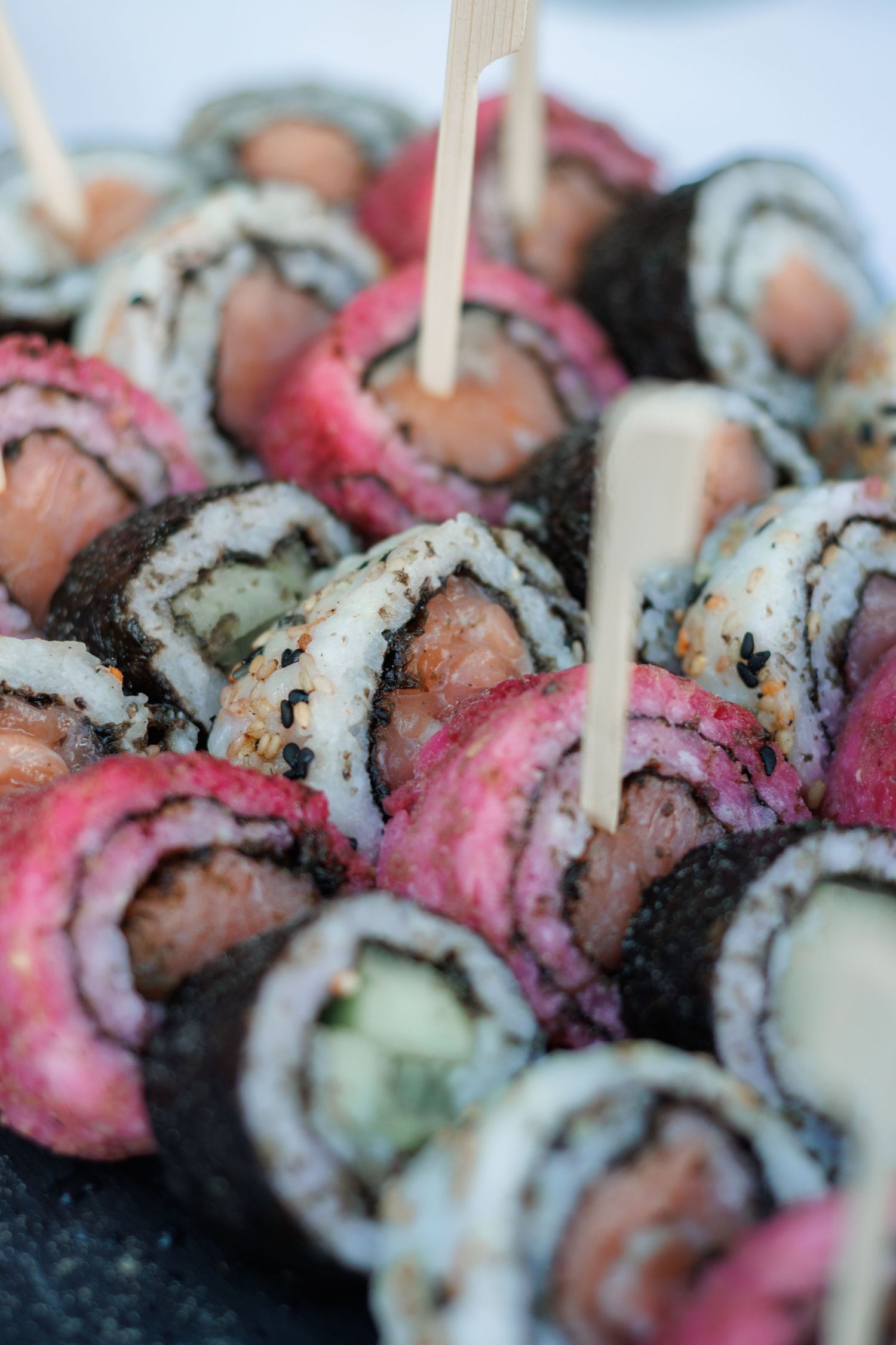 Assorted colorful sushi rolls with toothpicks on a platter at a wedding reception.