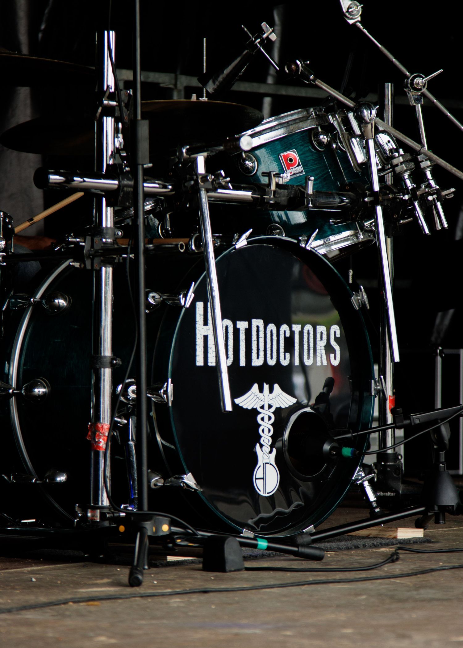 Drum kit setup with Hot Doctors logo on bass drum in dark stage lighting.