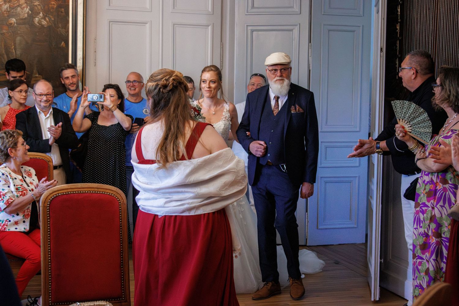 Bride and elderly man in blue suit making grand entrance at elegant wedding reception hall.