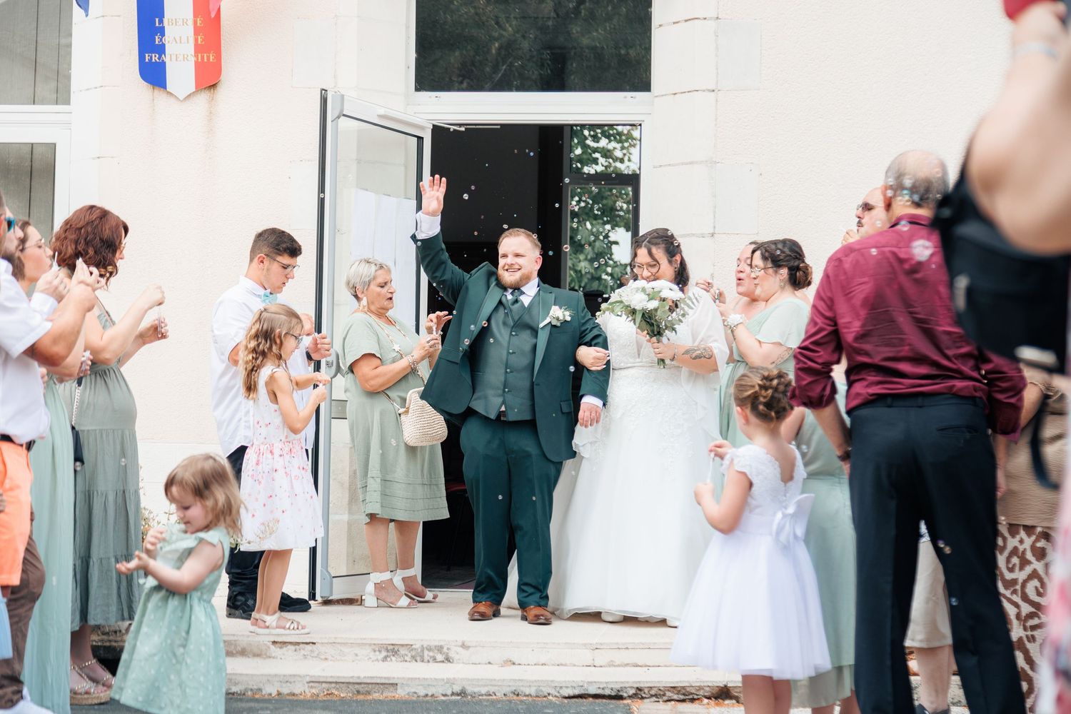 Joyful newlyweds exit ceremony hall as guests celebrate with confetti and applause outside.