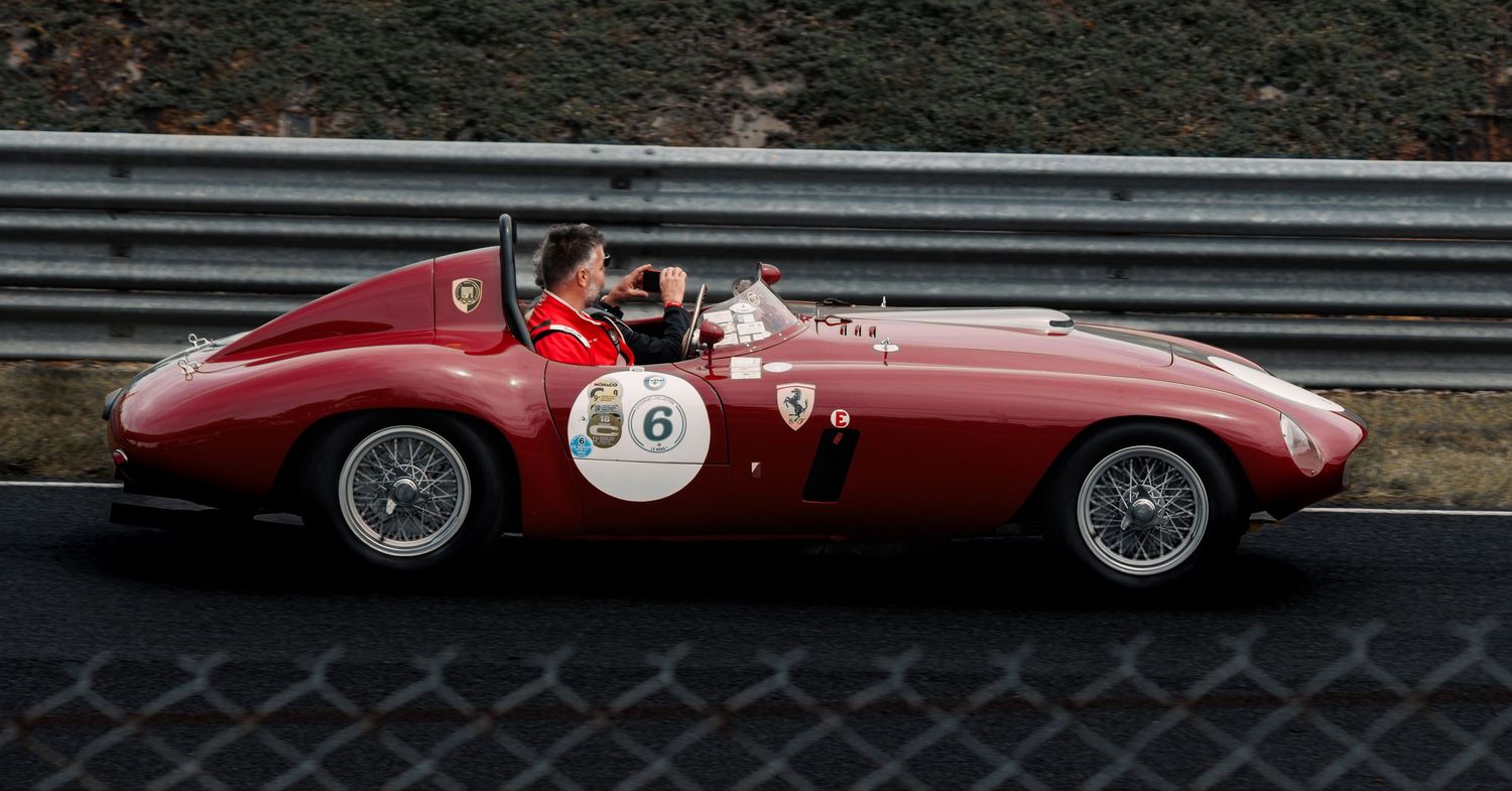 Classic red Ferrari racing car on track with vintage racing livery and racing number.