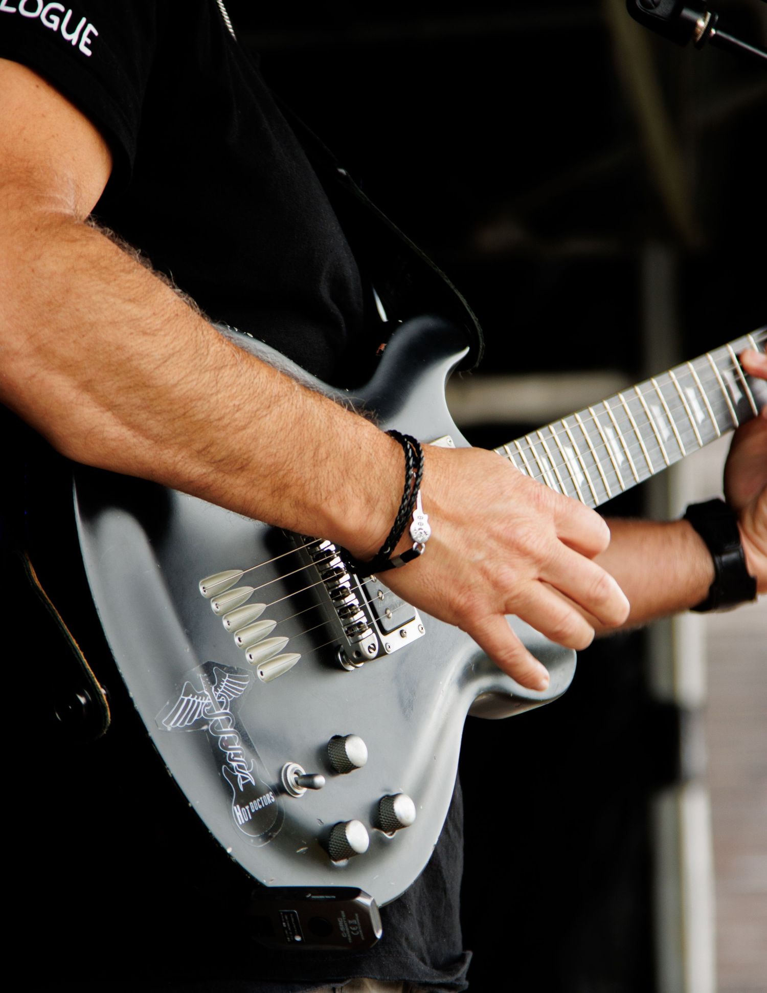 Close-up of hands playing a silver electric guitar with chrome hardware and pickups.
