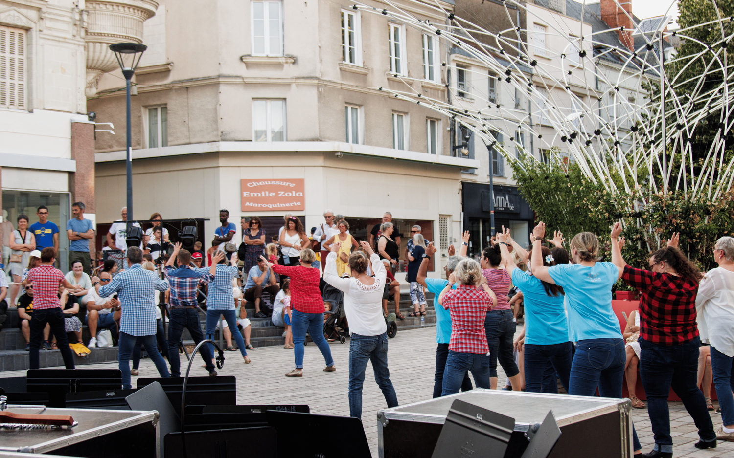 Large crowd of people dancing together outdoors on a street during a community event.
