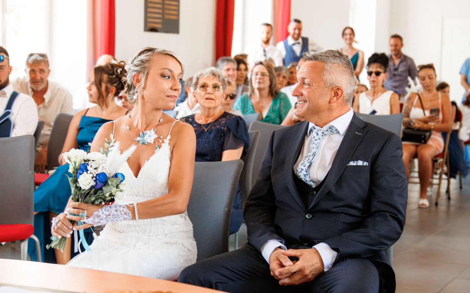 A wedding ceremony taking place in an indoor venue with decorative furnishings.