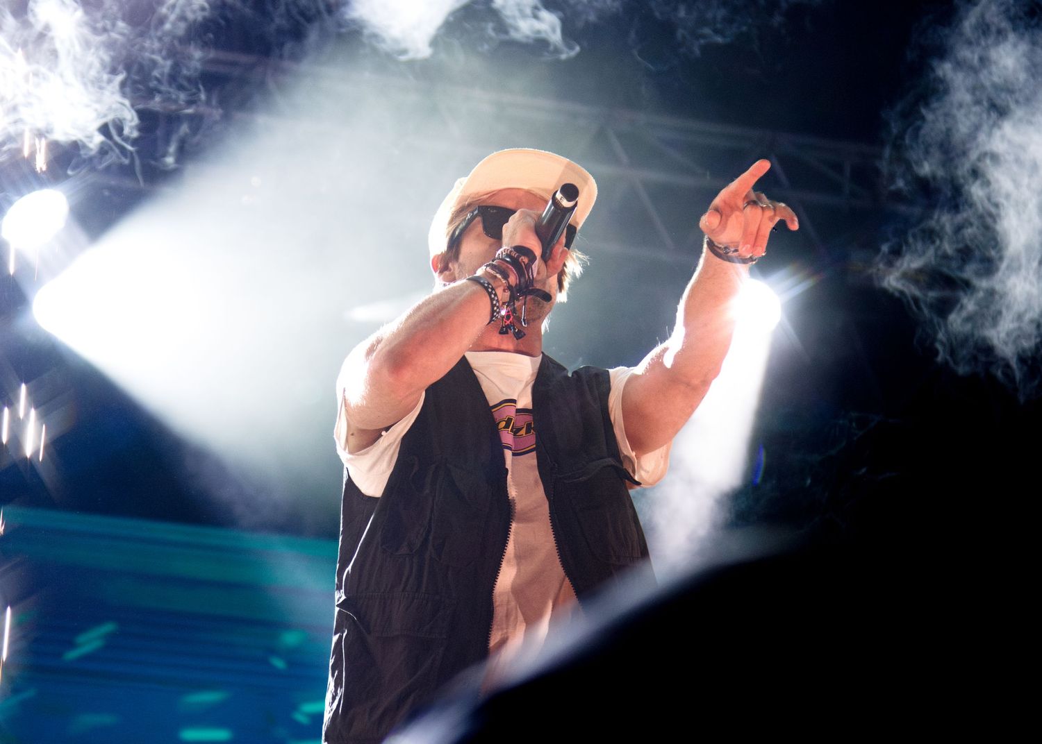 Stage performer singing passionately under dramatic blue and white spotlights during a concert performance.