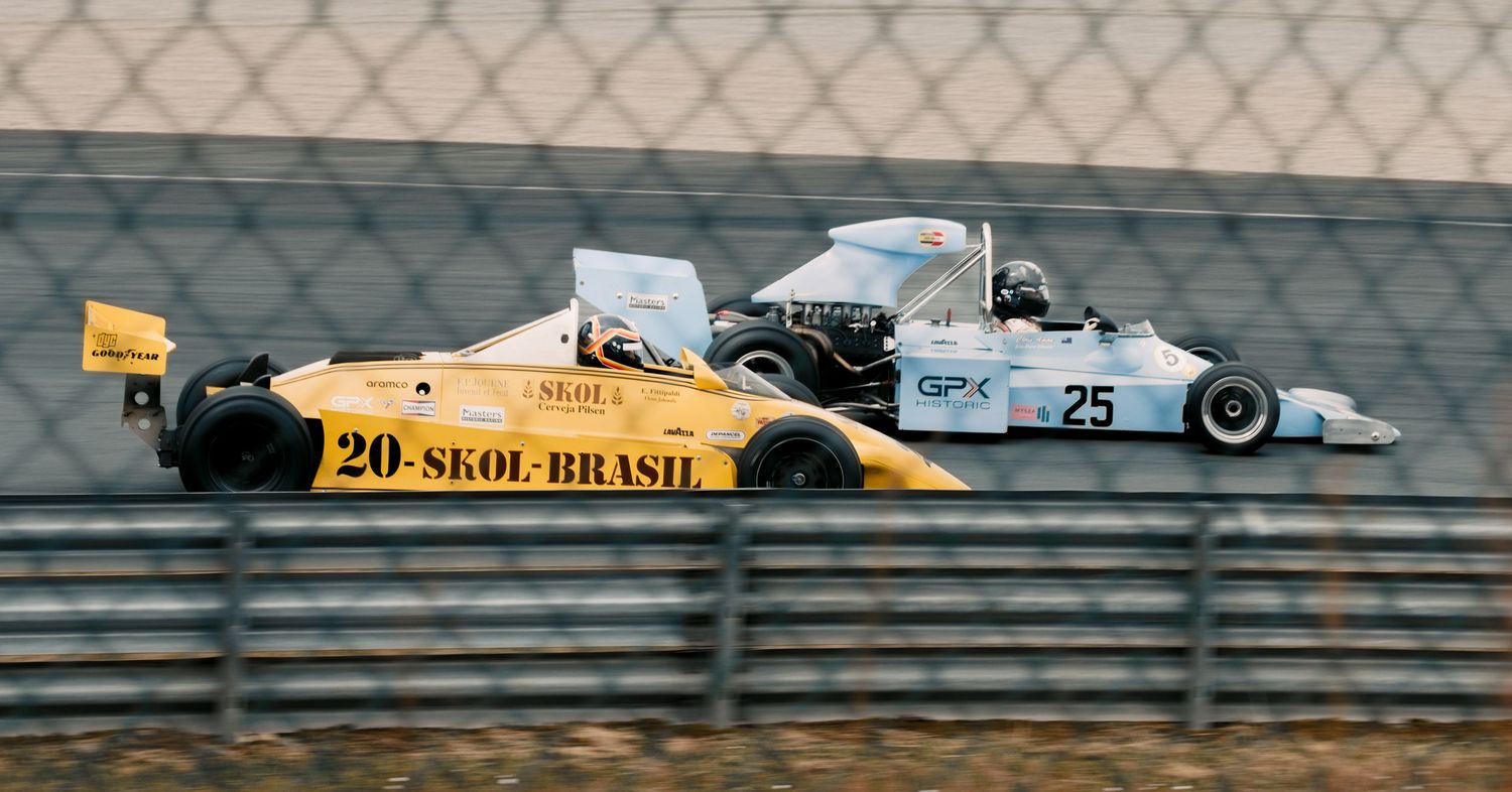 Racing cars including yellow Senna Brasil car compete on professional circuit.