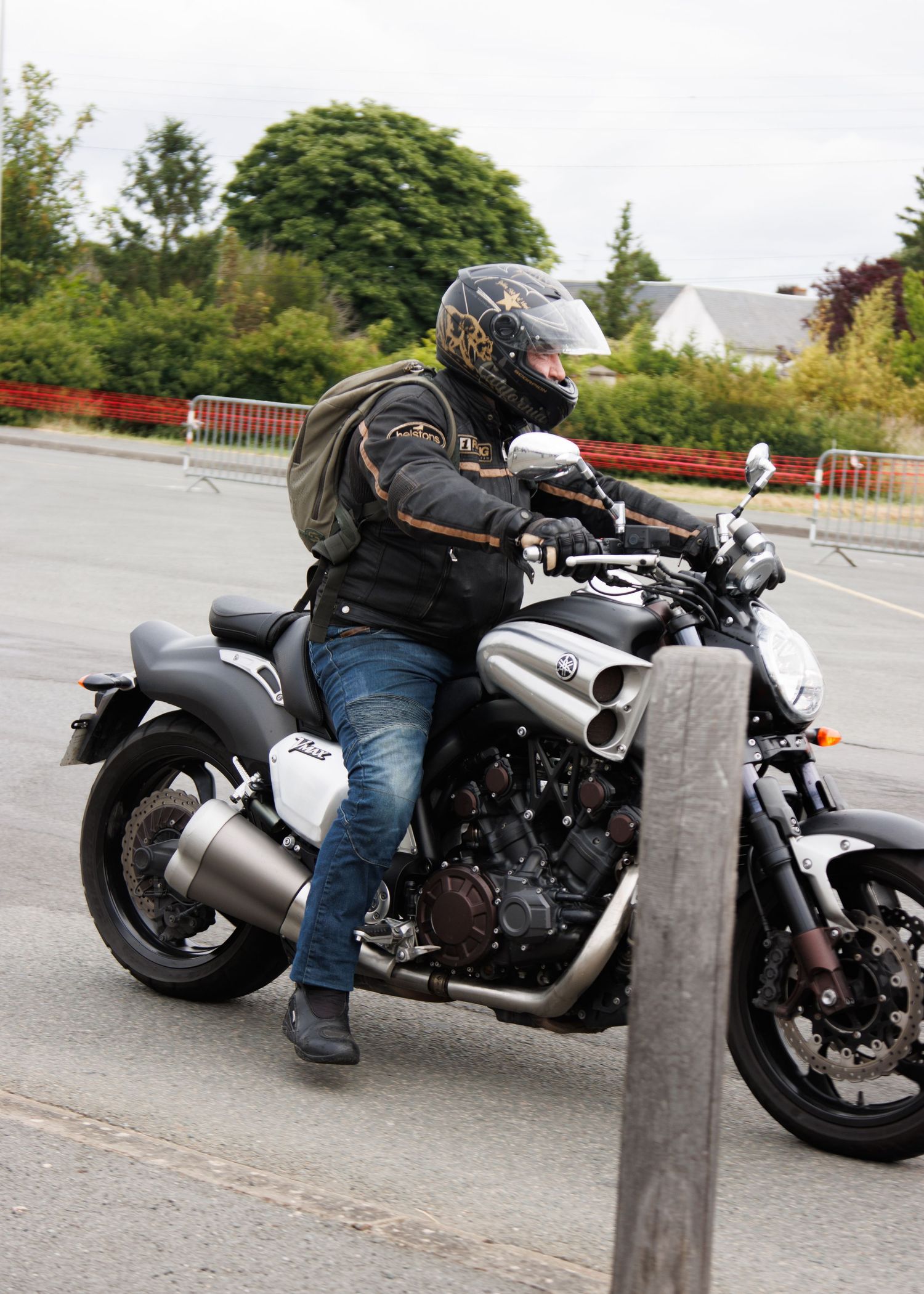 Motorcyclist in protective gear riding silver sport bike on curved road.