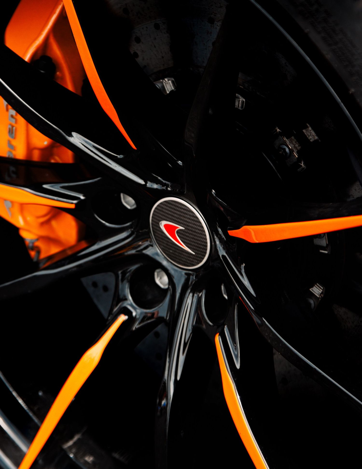 Close-up of black and orange McLaren wheel with distinctive spoke design.
