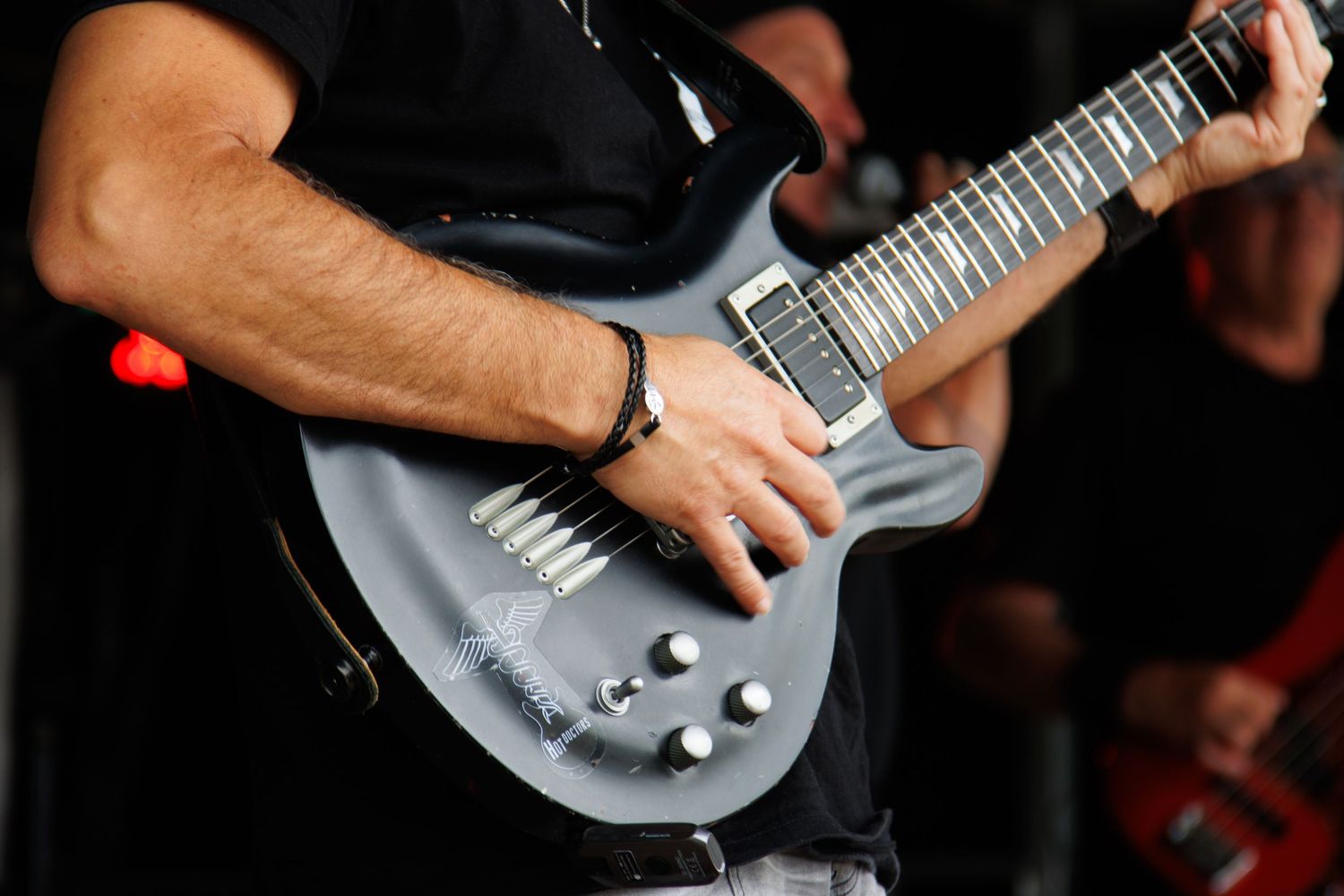 Close-up shot of hands playing a metallic gray electric guitar during performance.