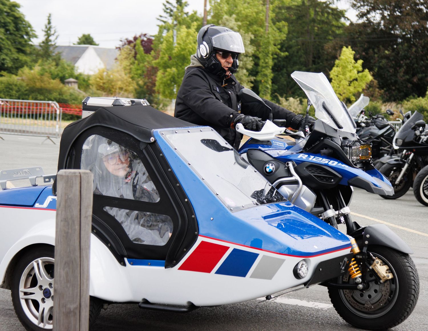 Rider on unique BMW motorcycle sidecar configuration at outdoor gathering.