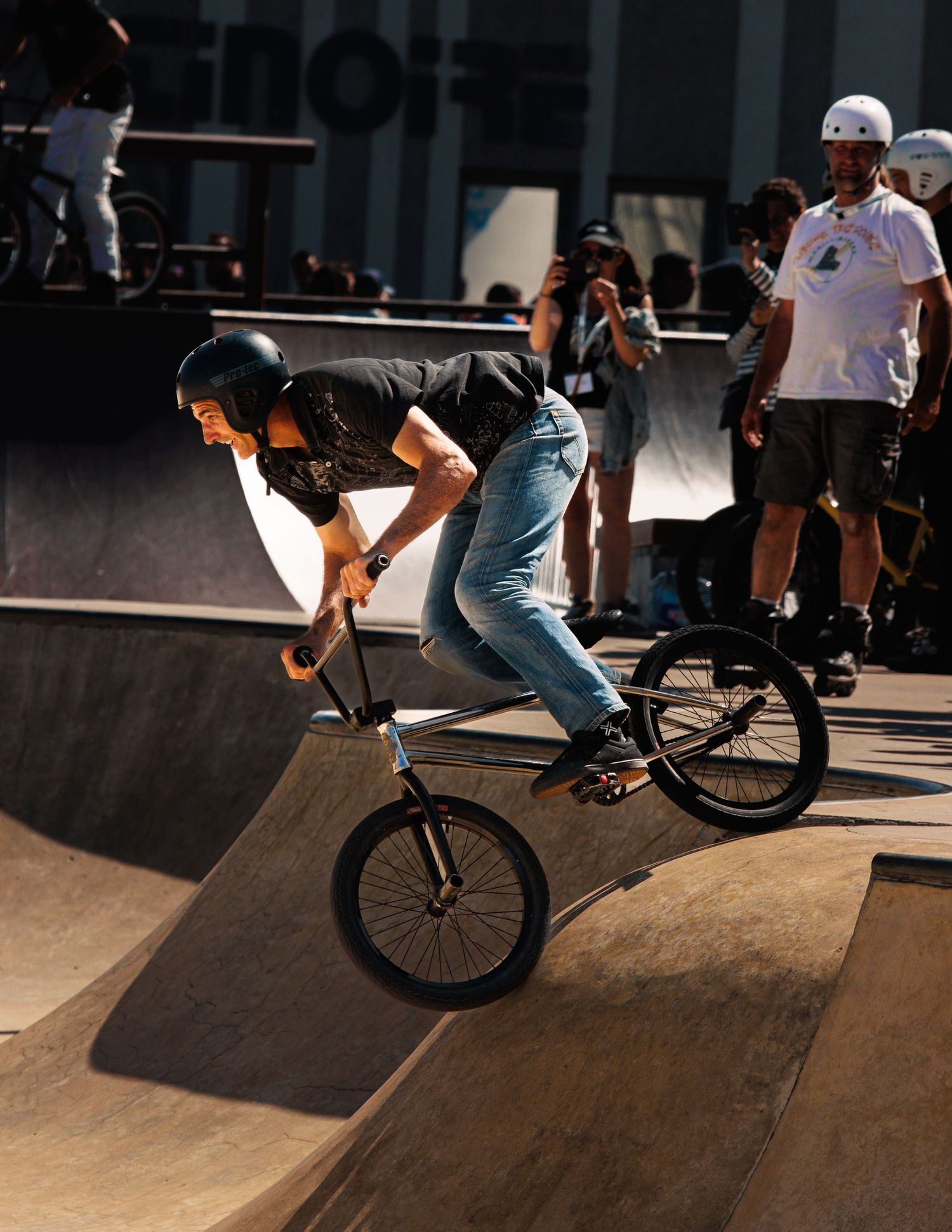 BMX rider executing trick on wooden ramp at indoor skate park.