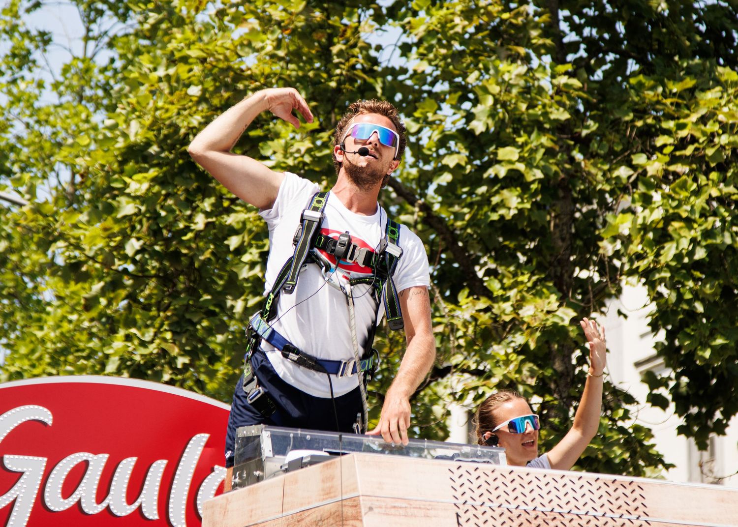 Enthusiastic participant gesturing from promotional vehicle during cycling event.