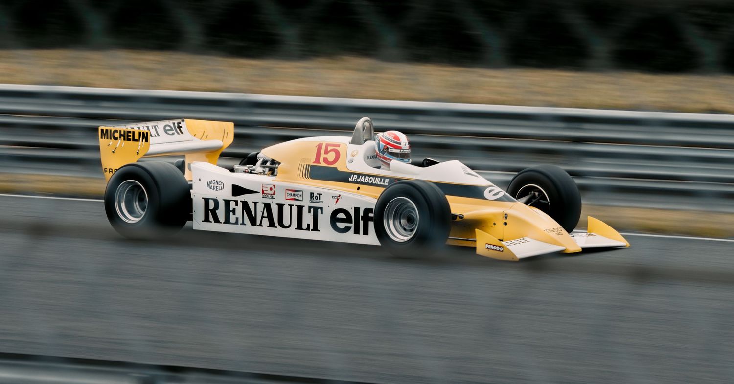 Yellow Renault Formula One car races at high speed on a professional racing circuit.