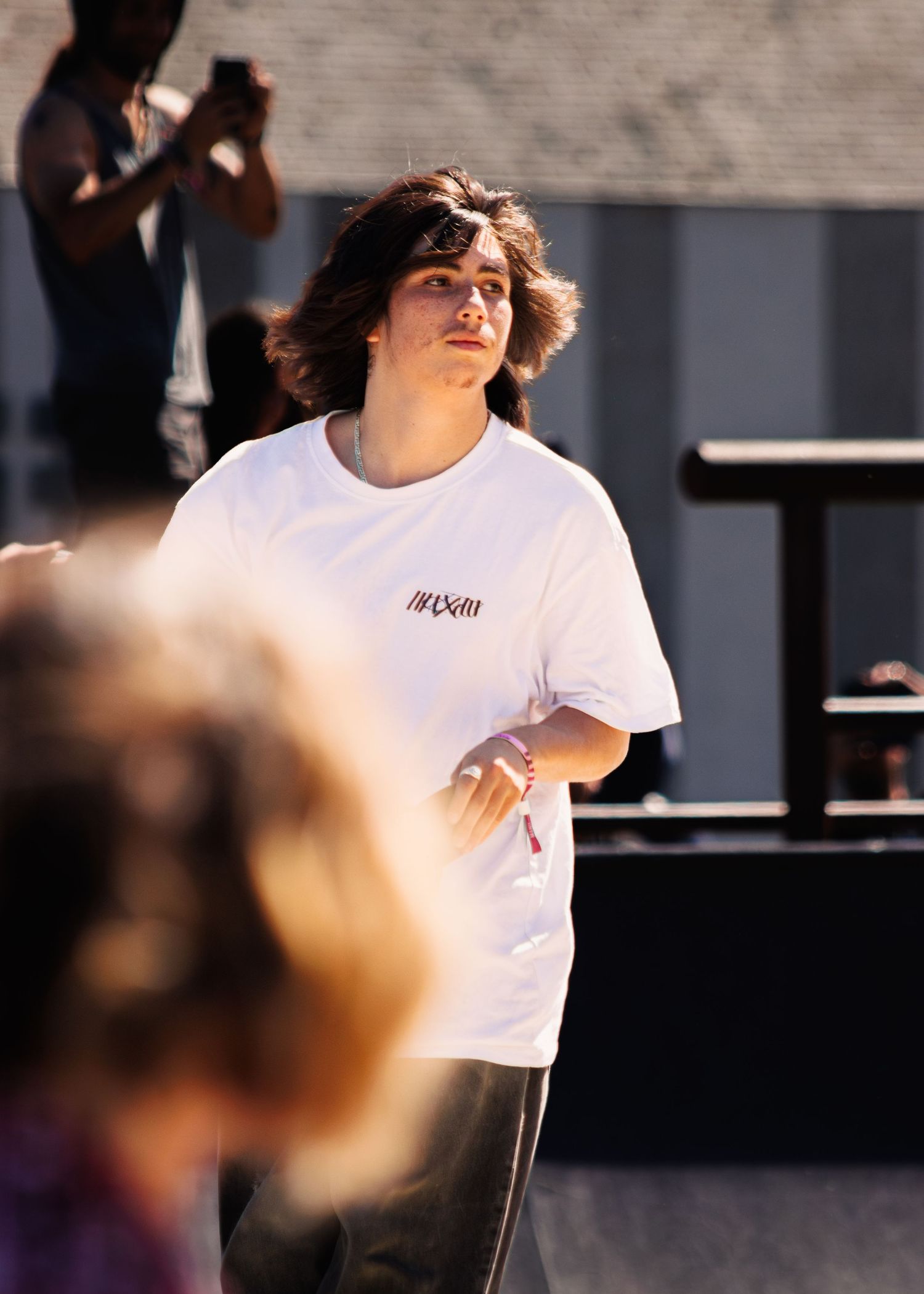 Skater in white t-shirt performs aerial tricks at outdoor skatepark.