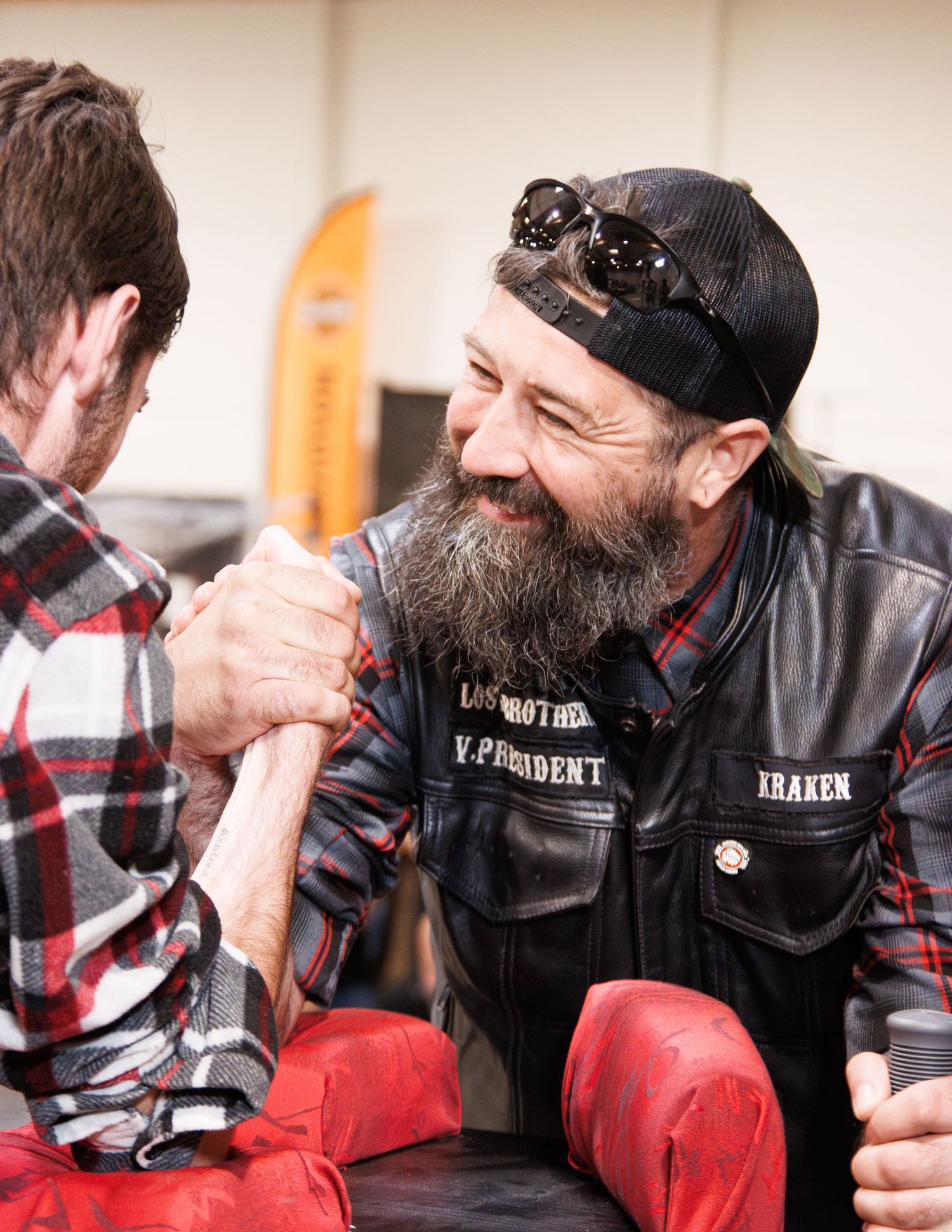 Two participants competing in friendly arm wrestling match while others watch.