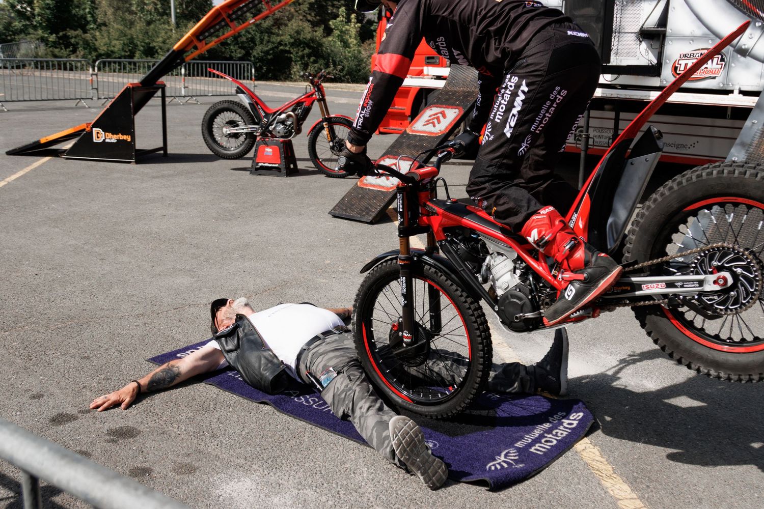 Stunt cyclist rides over a person lying on the ground during a thrilling bike trial performance outdoors.