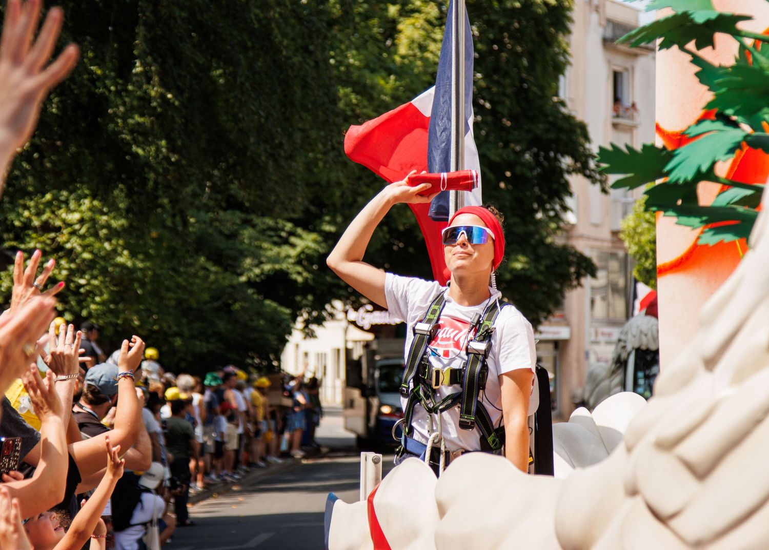 A parade participant waves to the crowd while standing on a moving float.