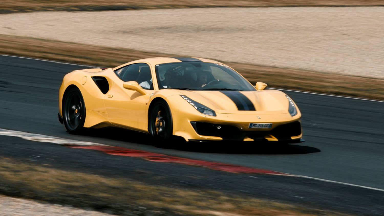 Yellow Ferrari 488 Pista performs on racetrack during track day event.