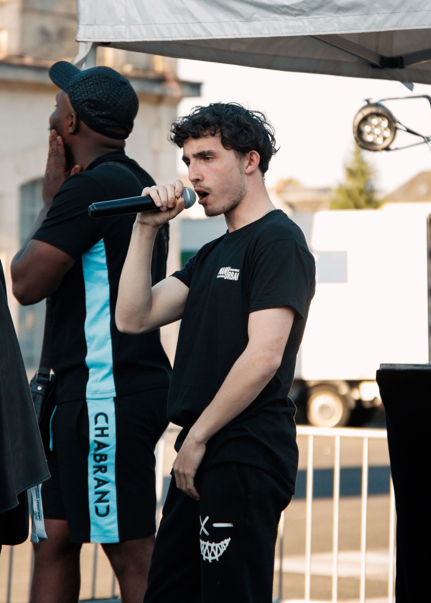 Performers on stage at outdoor event holding microphones.