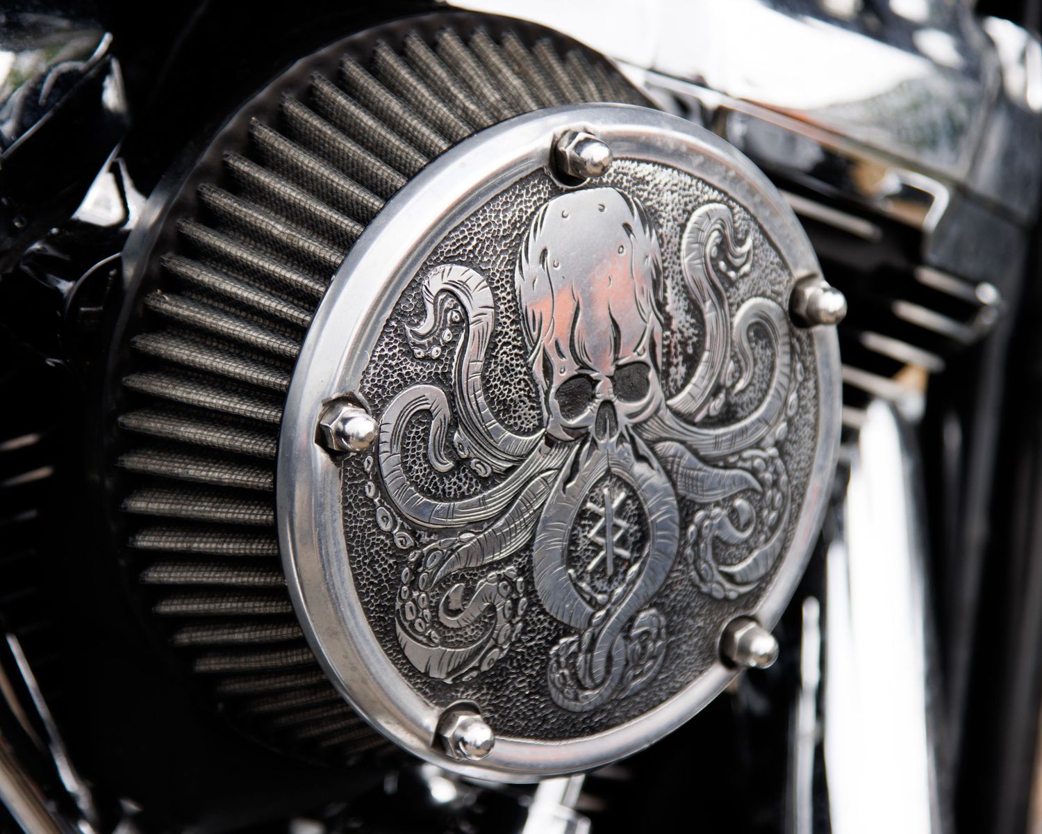 A detailed octopus design engraved on a motorcycle air filter cover.