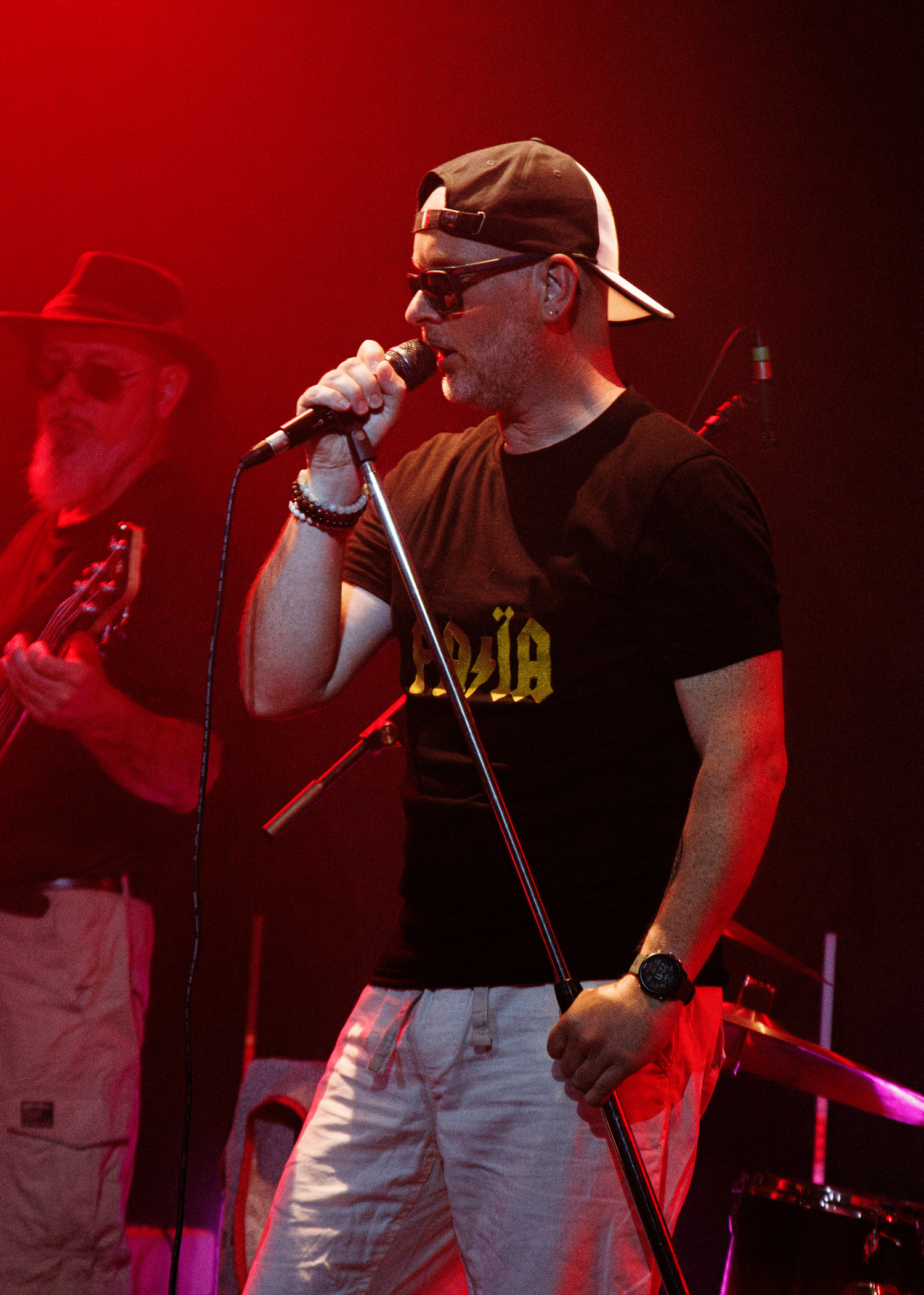 Band members singing and performing under dramatic red stage lights.