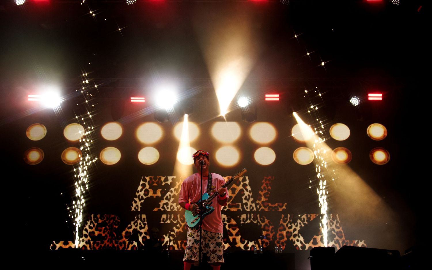 Dramatic concert stage with bright spotlights, bokeh effects and pyrotechnic sparkler fountains creating a spectacular atmosphere.