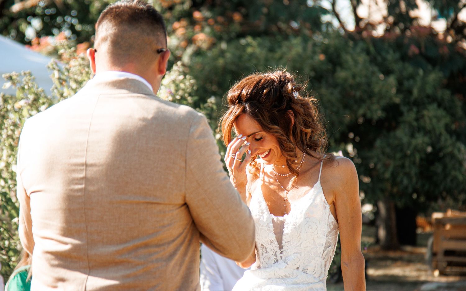 A couple shares a joyful moment together outdoors during their summer wedding ceremony.