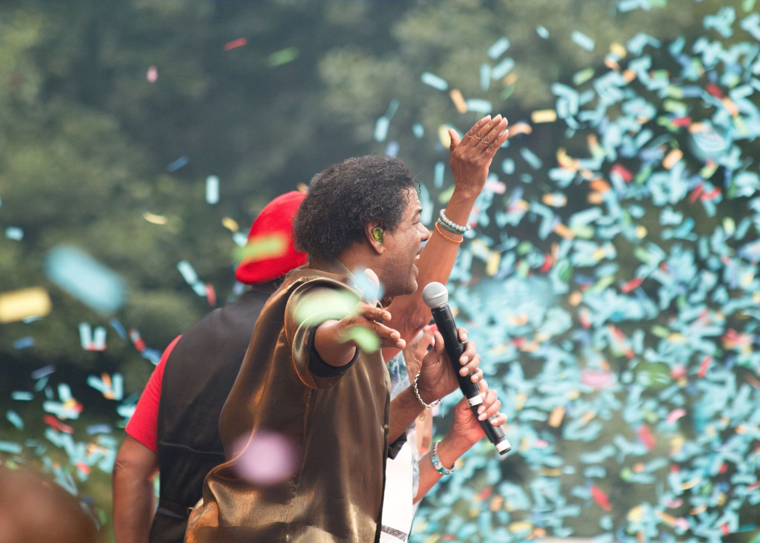 Performers on stage celebrate with confetti falling during a joyous outdoor concert performance.