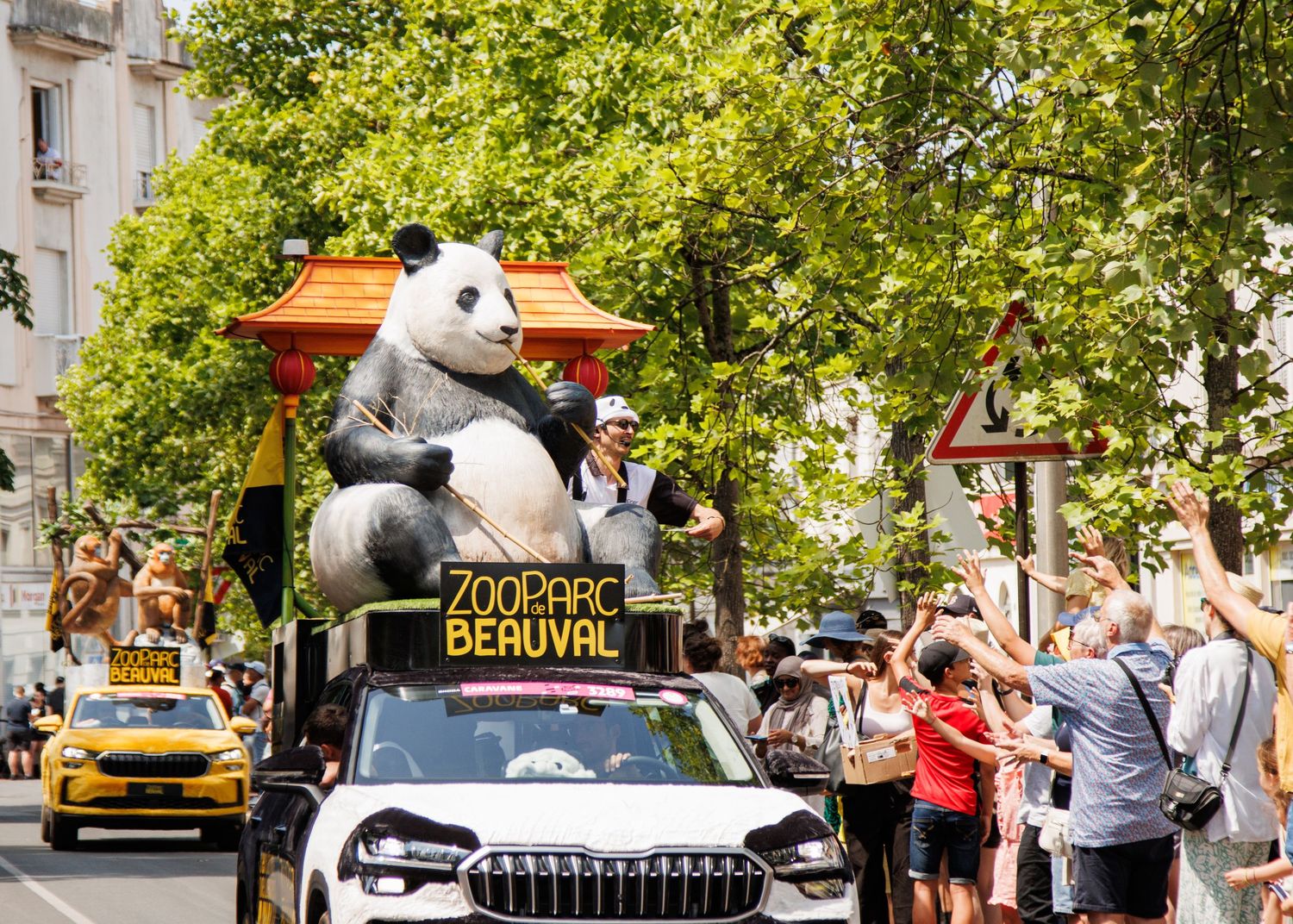 Large panda mascot display mounted on vehicle during urban street parade.