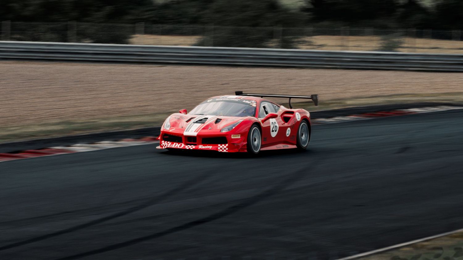 Red Ferrari FXX-K race car speeds through track corner with motion blur.
