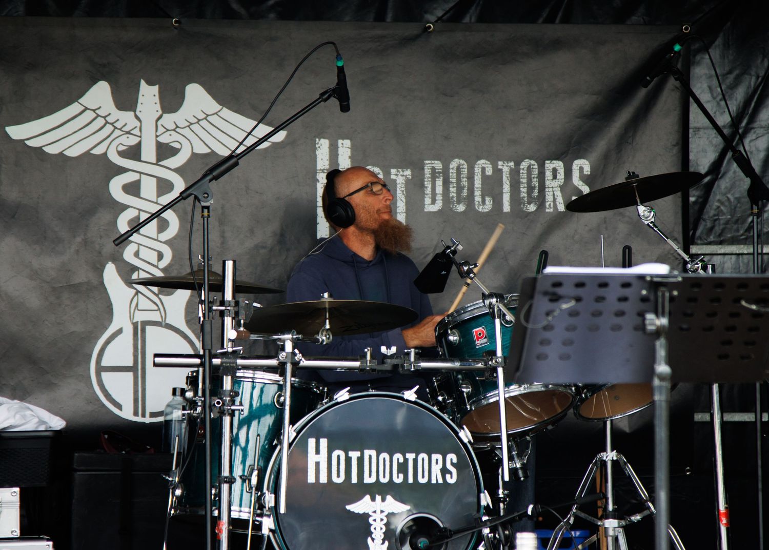 Band performing on dark stage with 'HotDoctors' logo visible in background.