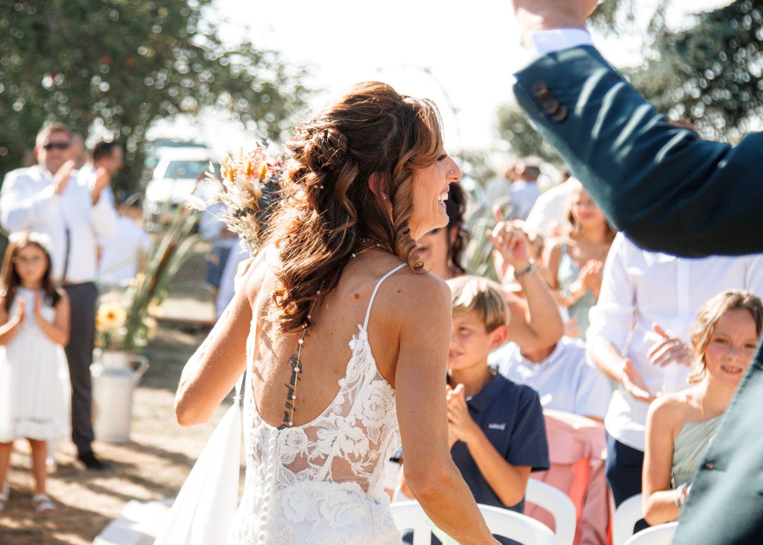 People celebrating at an outdoor event as confetti fills the air on a sunny day.