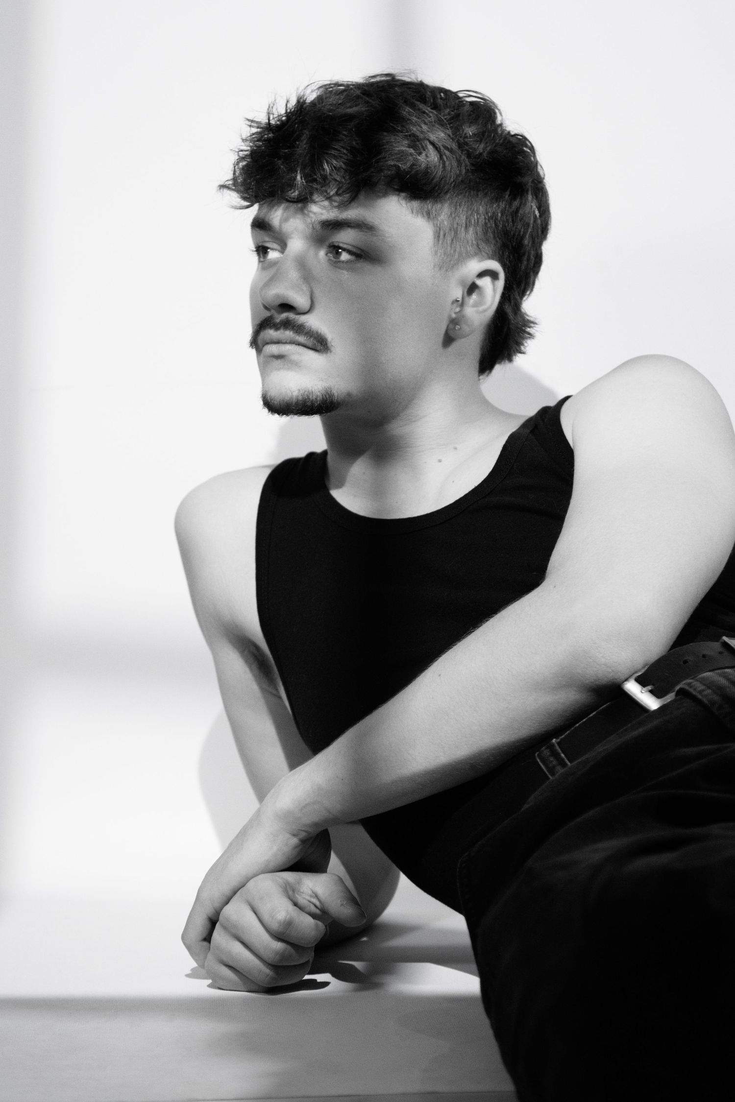 A black and white artistic photo series showing a person in a black shirt leaning on their arm in contemplative poses.