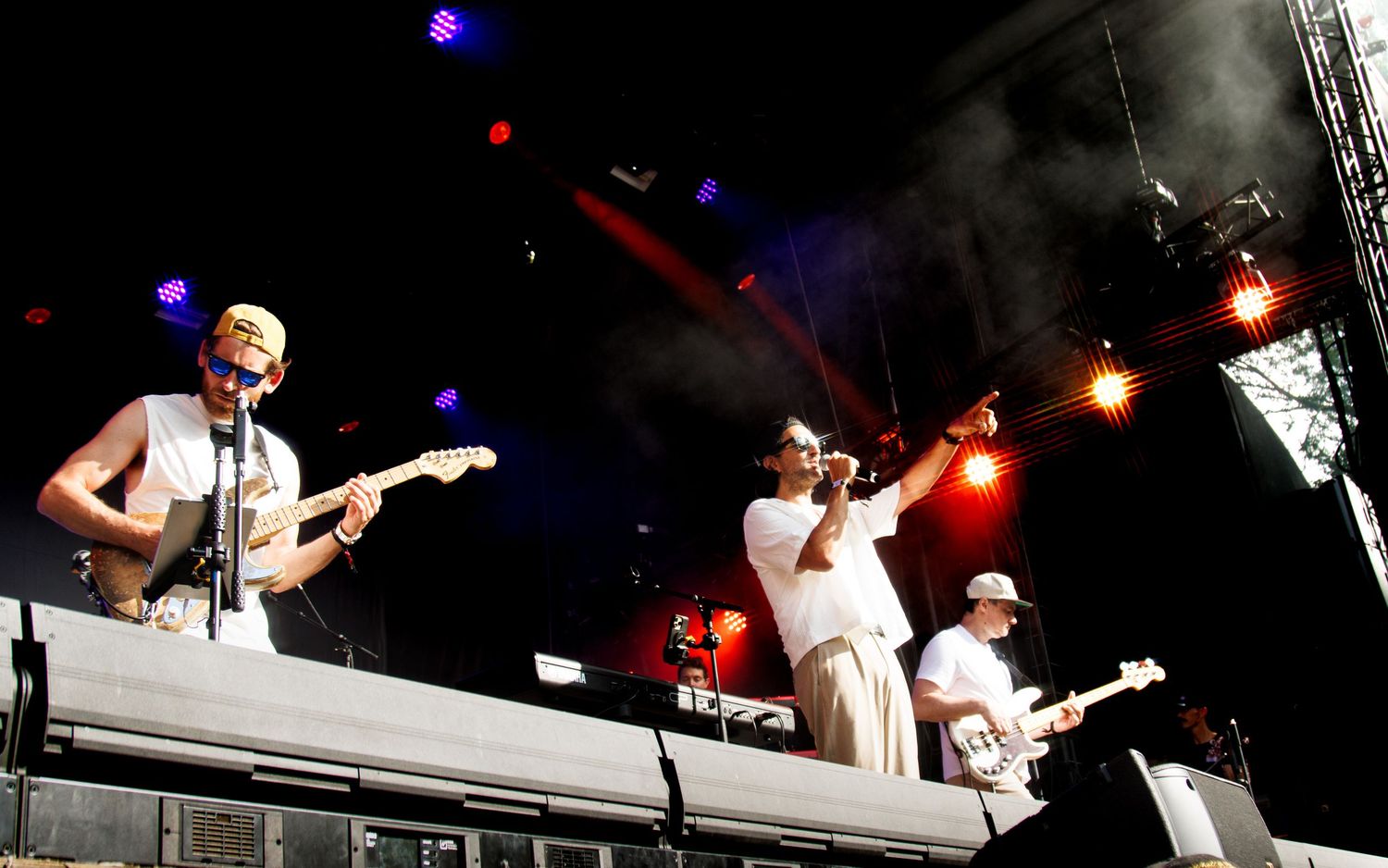 Musicians perform on stage during a live concert with dramatic lighting and multiple instruments.