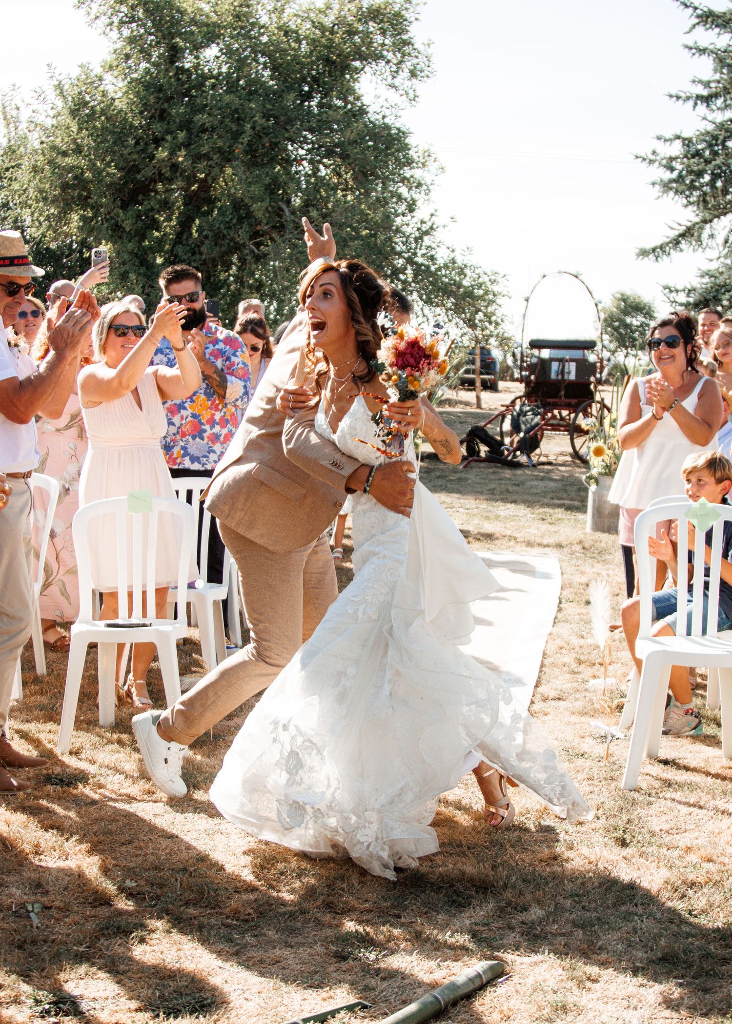 Wedding party forms a playful conga line at an outdoor summer ceremony celebration.