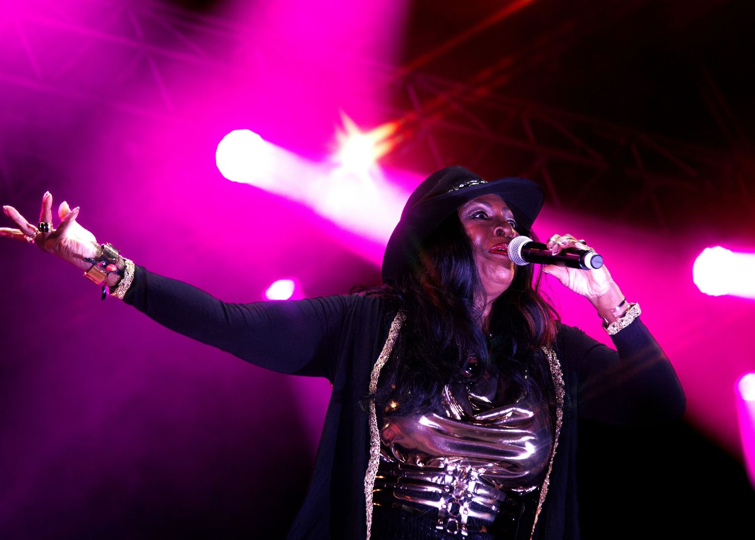 Singer performs passionately on stage with dramatic lighting and purple spotlights in the background.