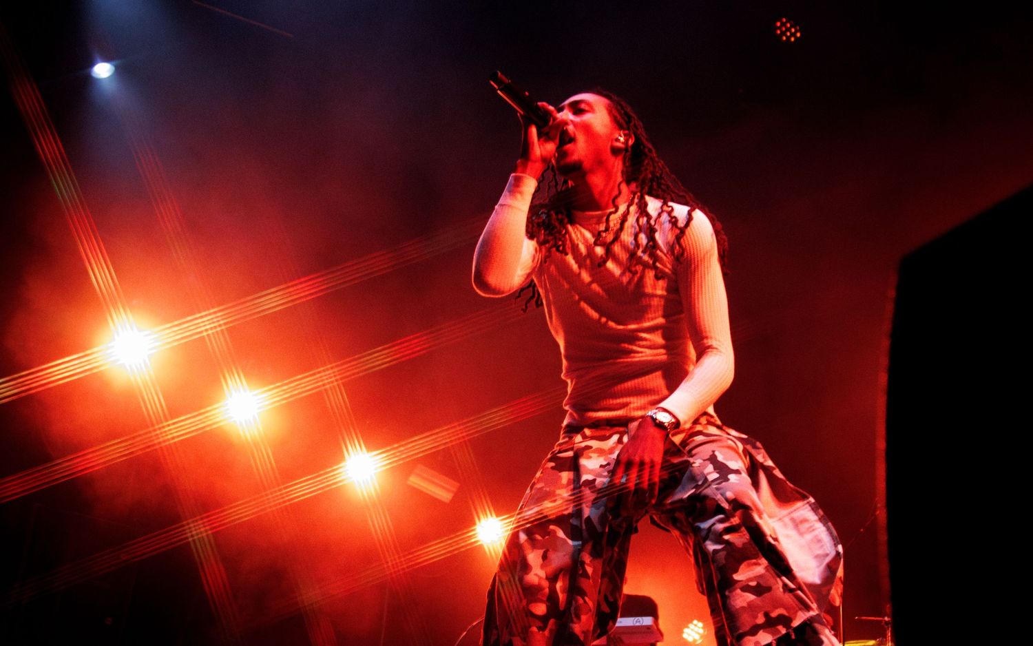 Rock singer performing on stage with dramatic red lighting and smoke effects at a live concert.